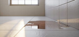 Fuktskada i badrum, tecken på vattenläcka med vita kakelplattor och fukt på golvet.