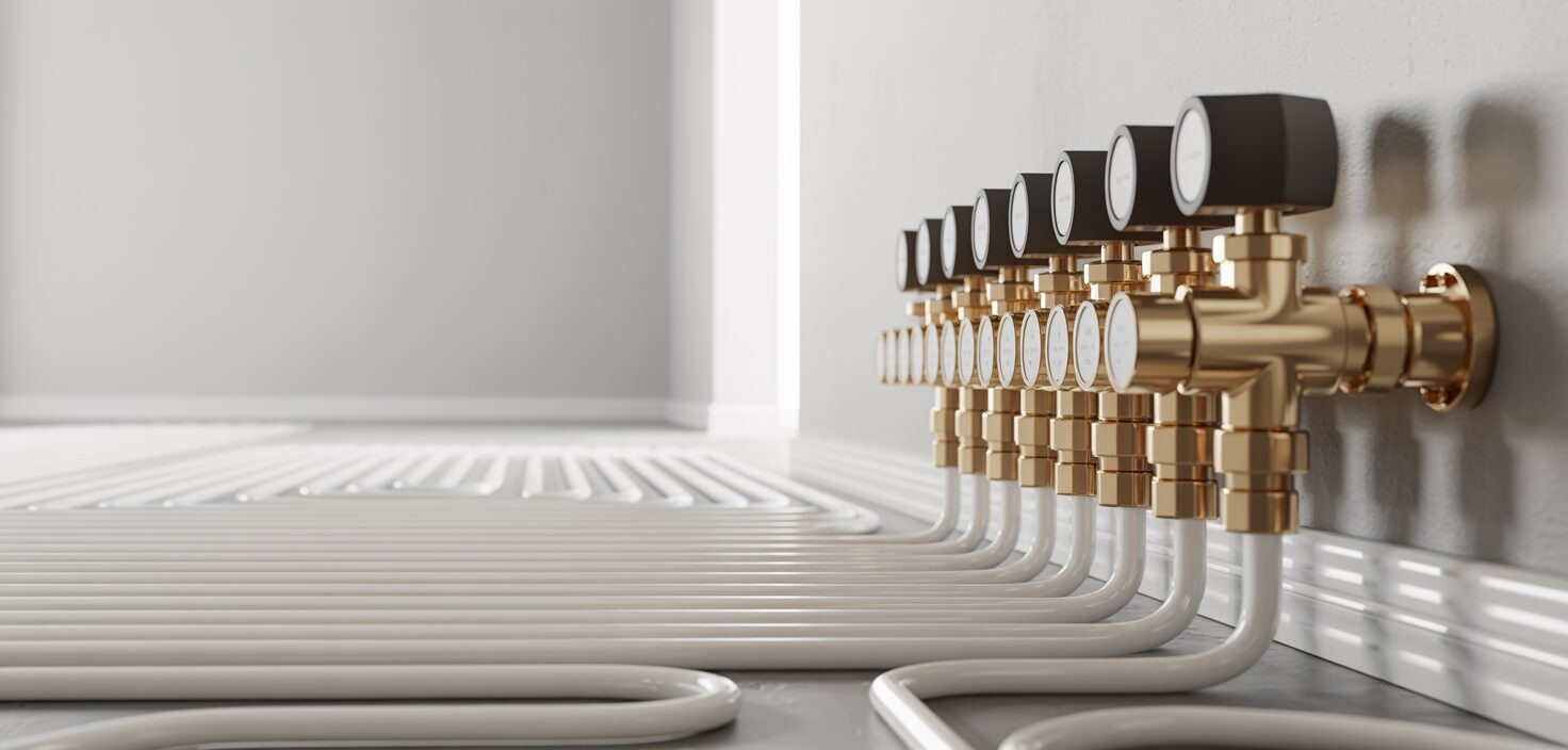 Golvvärmefördelare med flödesmätare på en vit vägg. En ren och minimalistisk installation.